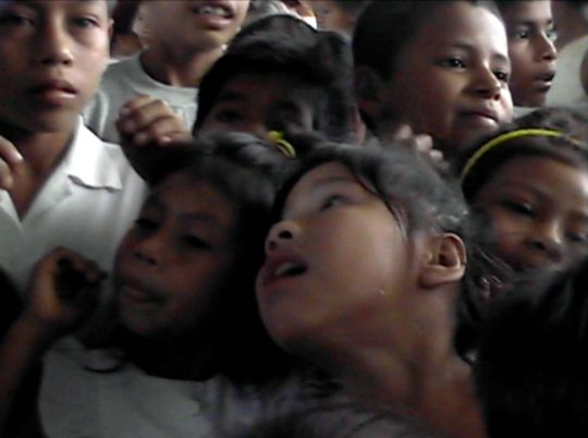 Girls reach for balloon tosssed into crowd of children.